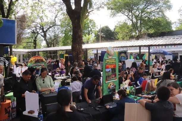 Wide view of a crowded school event with a Minecraft Education booth and visitors gathered around.