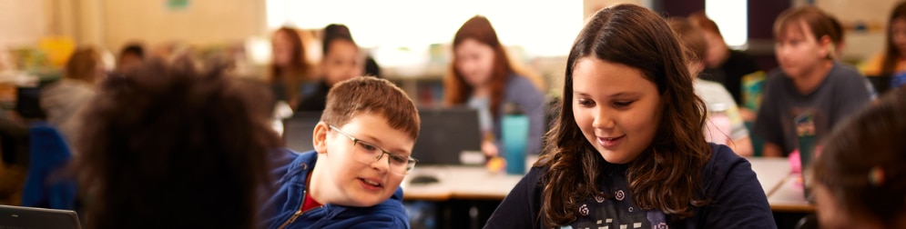 A boy and a girl looking into laptop in the classroom.
