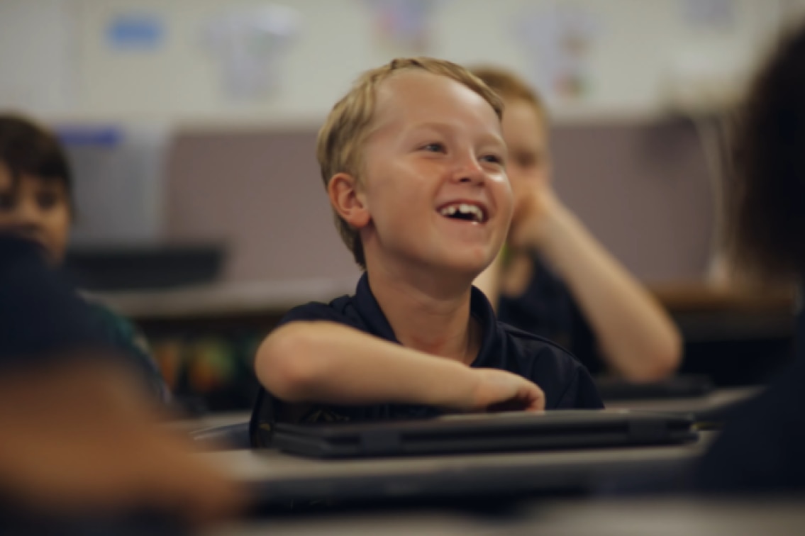 Student smiling while sitting in a classroom.