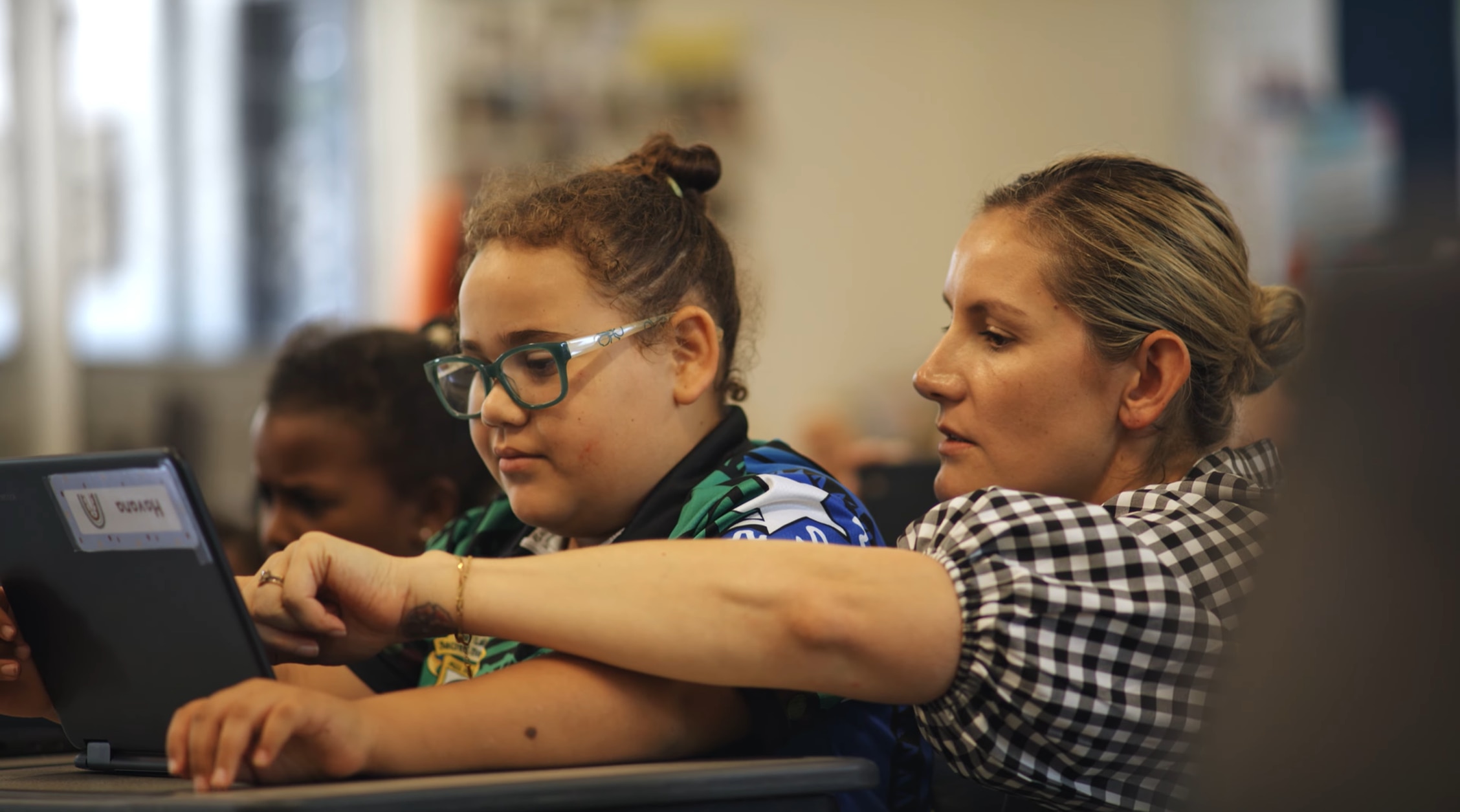 Teacher helps a student use a laptop in the classroom.