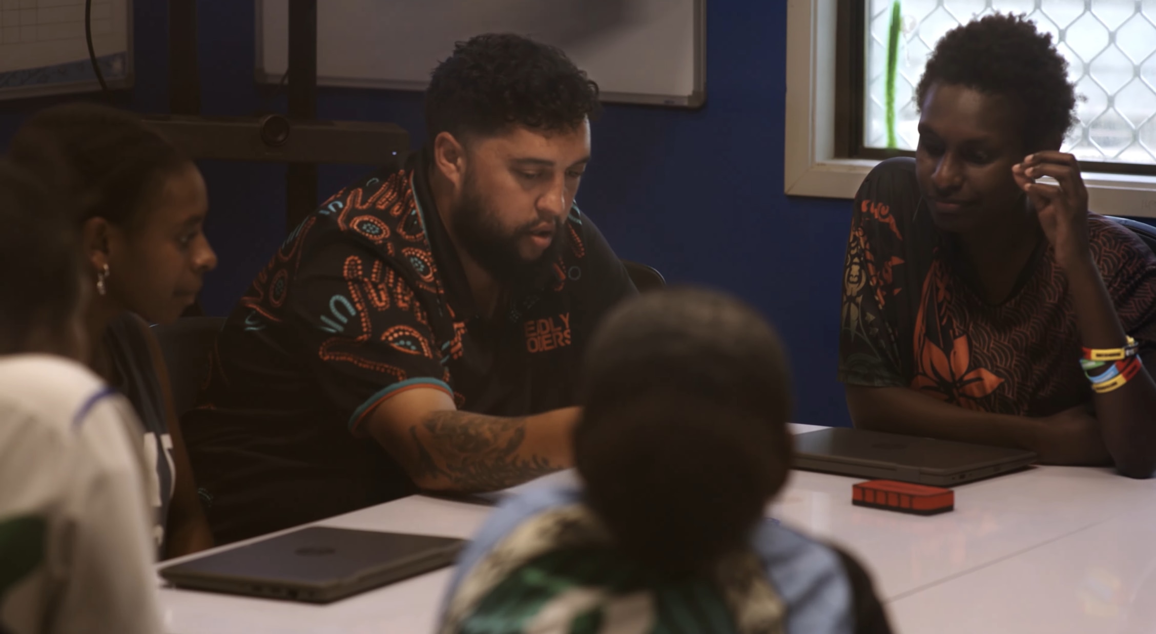 Educator and students sit together during a classroom discussion.