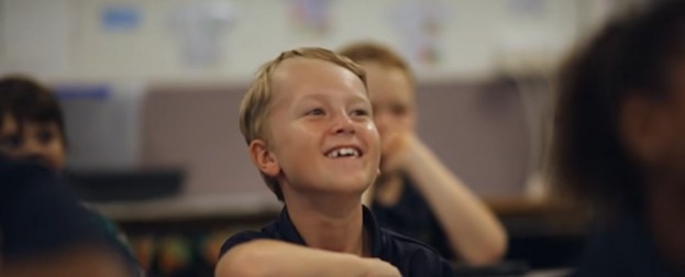 Student smiling while sitting in a classroom.