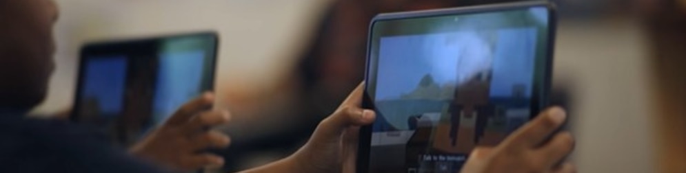 Students hold tablets showing Minecraft during a lesson.