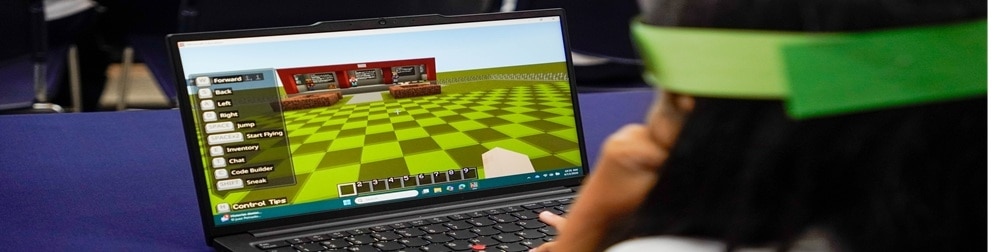 Student uses a laptop showing a Minecraft screen with movement controls and a code builder option.