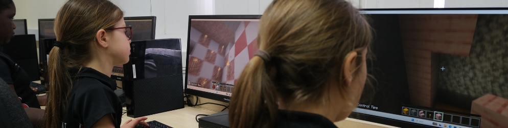 Students play Minecraft Education on computers in a classroom.