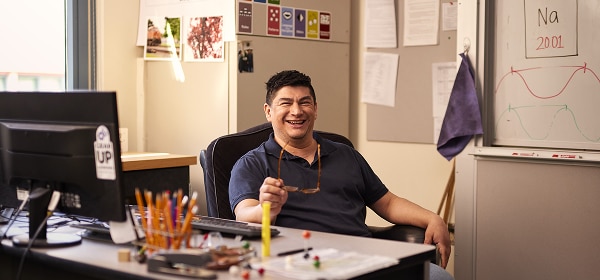 An instructor is sitting at their desk in a classroom.