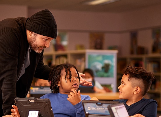 A teacher with two attentive students using tablets in a classroom.